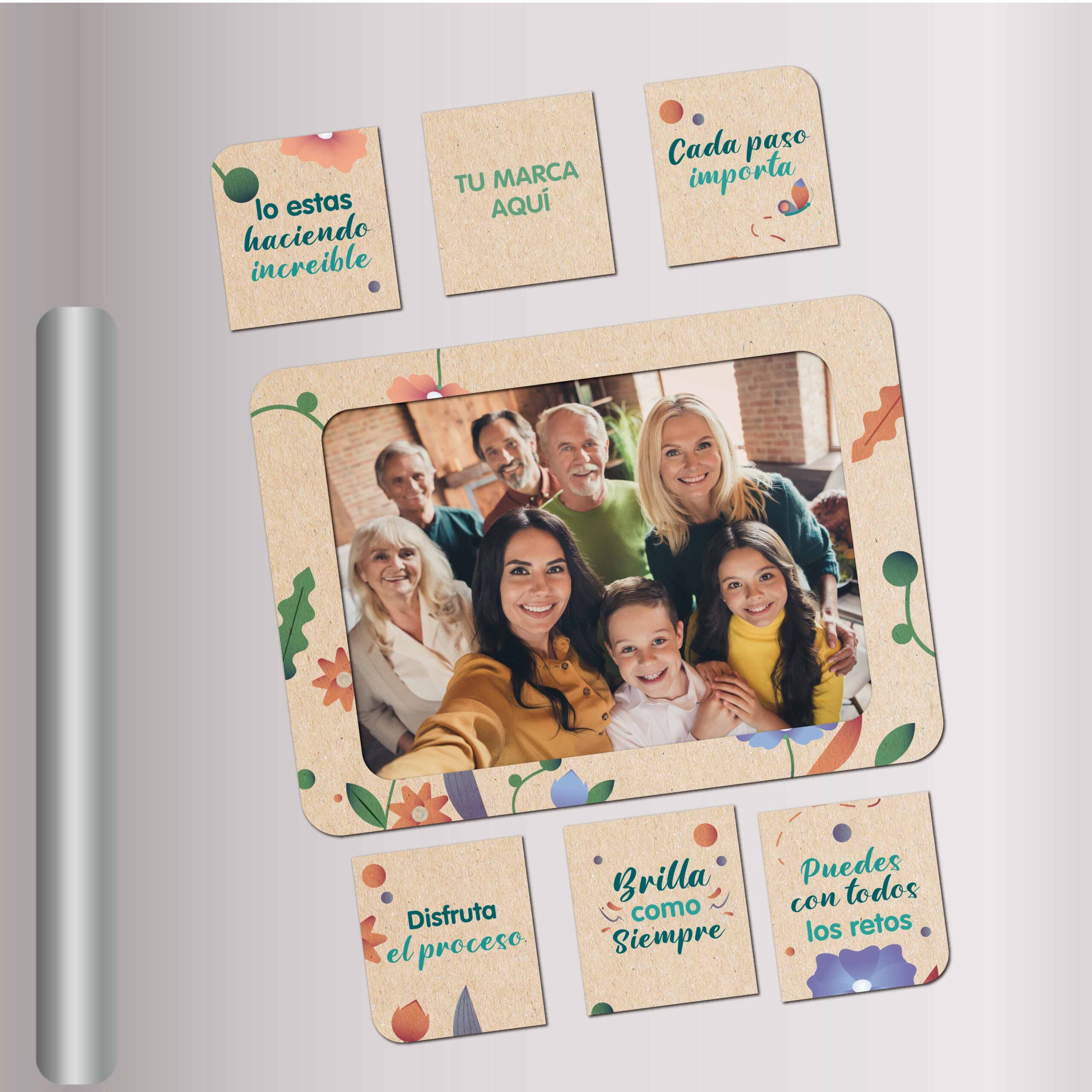 Portarretrato magnético ecológico con diseño floral y frases motivacionales, adherido a una nevera metálica. La imagen central muestra a una familia sonriendo. Incluye piezas imantadas adicionales con mensajes positivos como "Brilla como siempre", "Disfruta el proceso" y "Lo estás haciendo increíble". Producto de la subcategoría Línea Ecológica ideal para campañas con propósito y recordación emocional.
