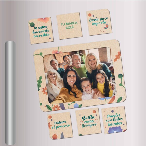Portarretrato magnético ecológico con diseño floral y frases motivacionales, adherido a una nevera metálica. La imagen central muestra a una familia sonriendo. Incluye piezas imantadas adicionales con mensajes positivos como "Brilla como siempre", "Disfruta el proceso" y "Lo estás haciendo increíble". Producto de la subcategoría Línea Ecológica ideal para campañas con propósito y recordación emocional.