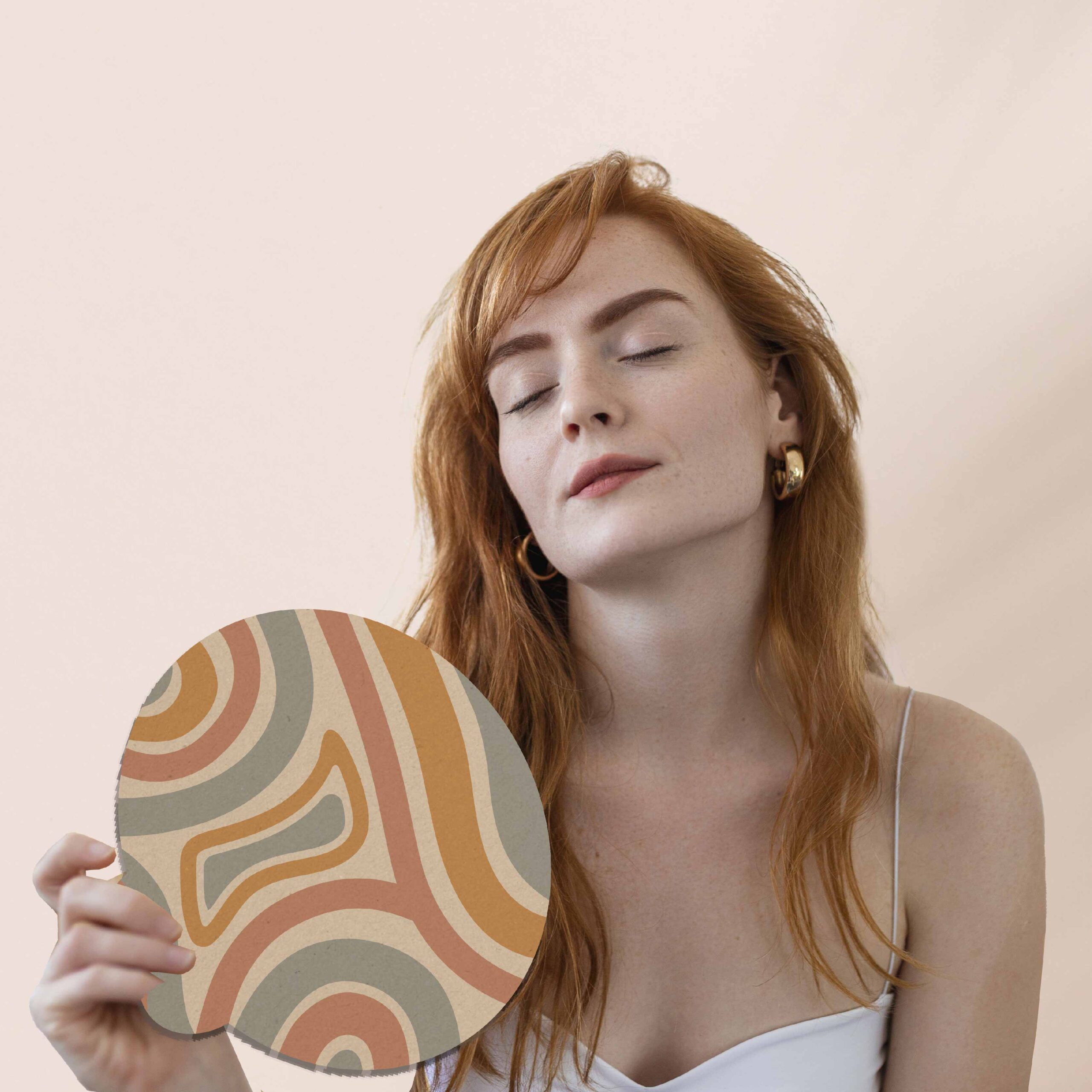 Mujer con expresión relajada sostiene un abanico ecológico redondo con diseño abstracto en tonos tierra. El abanico pertenece a la subcategoría Línea Ecológica de regalos corporativos, ideal para campañas sostenibles o de bienestar personal.