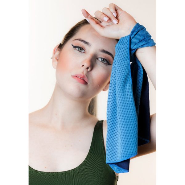 Chica con toalla refrescante de color azul en la mano como manilla lista para hacer deporte.