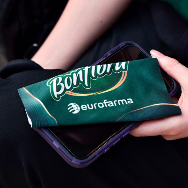 Paño de microfibra con la marca eurofarma cuidando de la pantalla del celular.